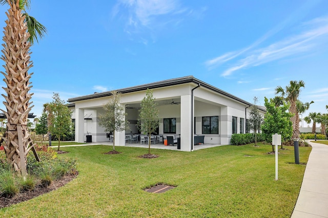 10571 SW Sunray St, Port Saint Lucie, FL 34987 - rear view of house with ceiling fan, an outdoor hangout area, stucco siding, a patio area, and a lawn