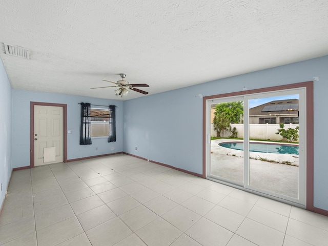 empty room featuring ceiling fan, a textured ceiling, and light tile patterned flooring