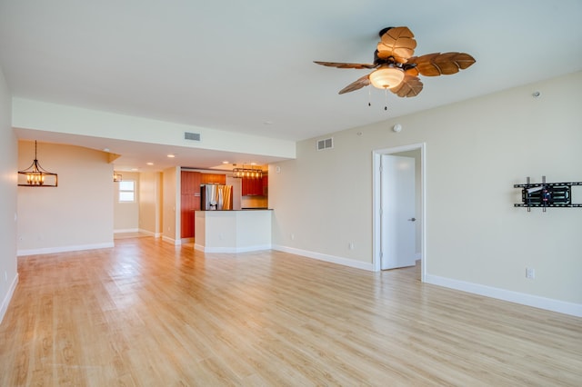 unfurnished living room featuring light wood-type flooring, visible vents, baseboards, and ceiling fan with notable chandelier