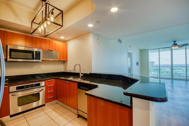 kitchen featuring a peninsula, stainless steel appliances, a wall of windows, a sink, and recessed lighting