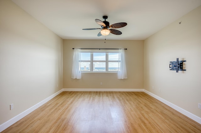 unfurnished room with a ceiling fan, light wood-type flooring, and baseboards