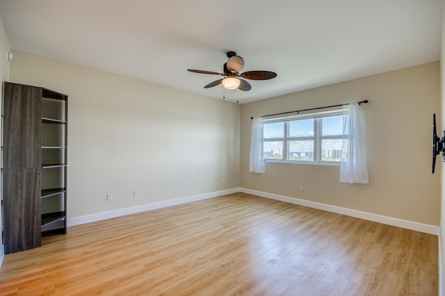 empty room featuring light wood finished floors, ceiling fan, and baseboards