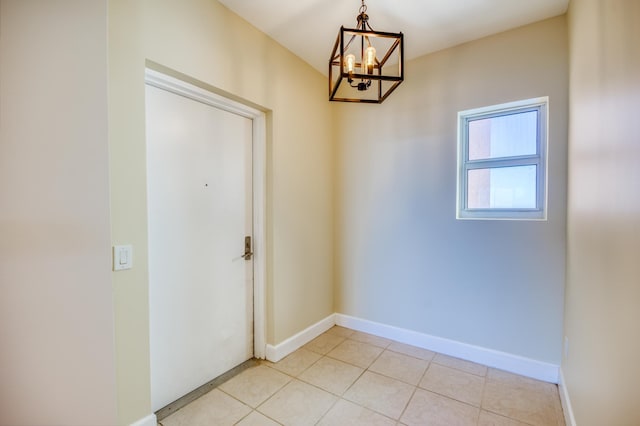 interior space featuring light tile patterned floors, a chandelier, and baseboards