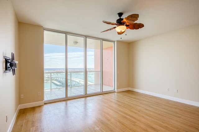 living room with a wall of windows, wood-type flooring, and ceiling fan