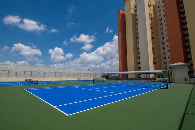 view of tennis court with community basketball court and fence