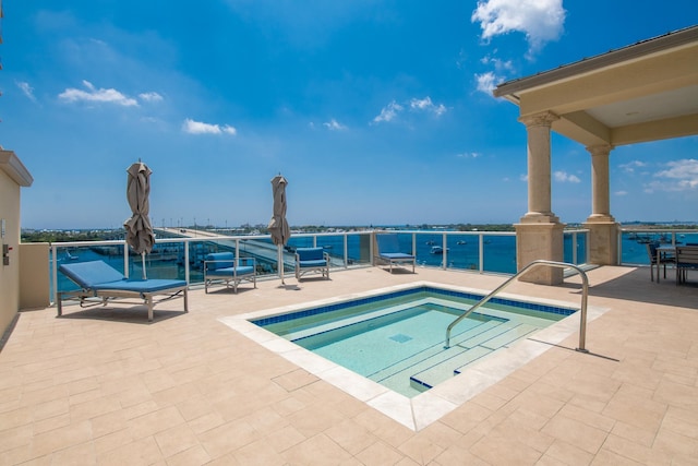 view of swimming pool featuring a patio area, a water view, and a hot tub