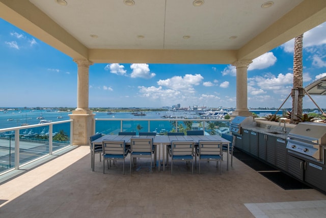 view of patio / terrace featuring outdoor dining area, a water view, a sink, and area for grilling