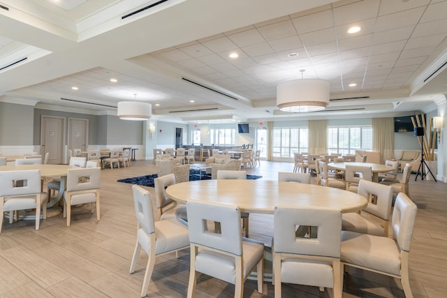 dining space with visible vents, a raised ceiling, light wood-style flooring, crown molding, and recessed lighting