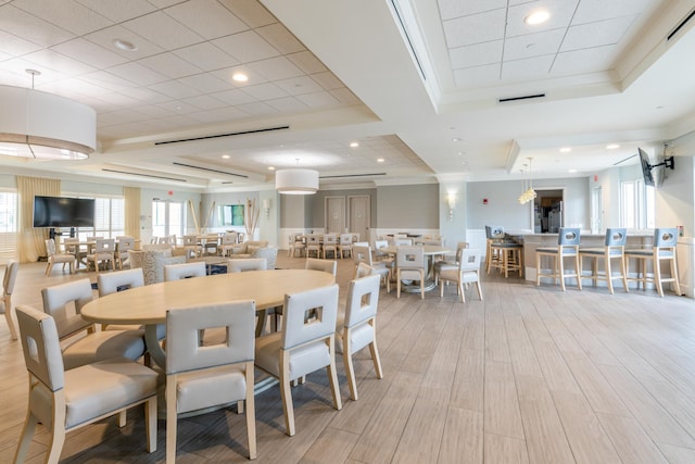 dining space with recessed lighting, a raised ceiling, crown molding, and wood finished floors