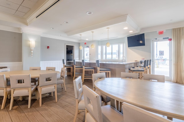 dining room with light wood-style floors, recessed lighting, a wainscoted wall, and crown molding