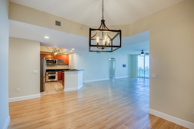 unfurnished living room featuring light wood finished floors, visible vents, a sink, baseboards, and ceiling fan with notable chandelier