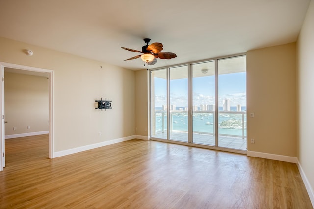 empty room with light wood-type flooring, baseboards, floor to ceiling windows, and a city view