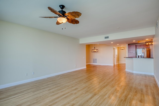 unfurnished living room featuring light wood-type flooring, visible vents, ceiling fan, and baseboards