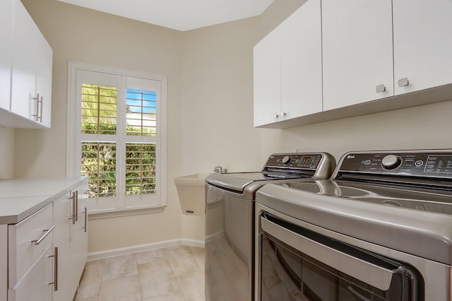 washroom featuring cabinets, light tile patterned flooring, and washing machine and dryer