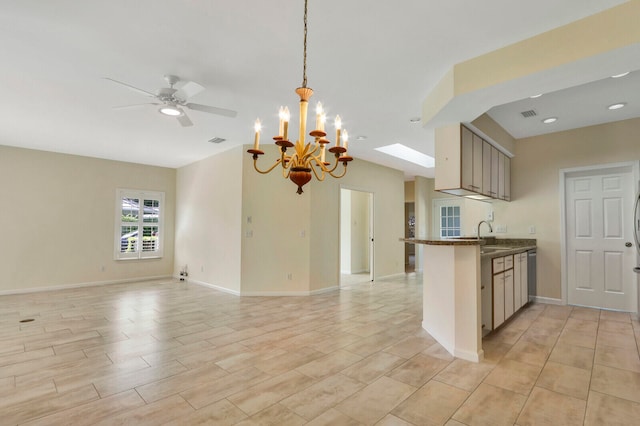 kitchen featuring ceiling fan with notable chandelier, kitchen peninsula, hanging light fixtures, light hardwood / wood-style flooring, and a skylight