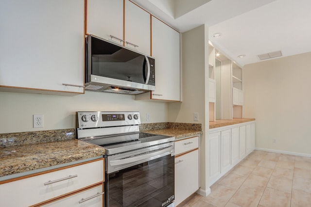 kitchen with dark stone counters, stainless steel appliances, white cabinets, and light tile patterned floors