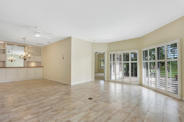 spare room with ceiling fan with notable chandelier and a wealth of natural light