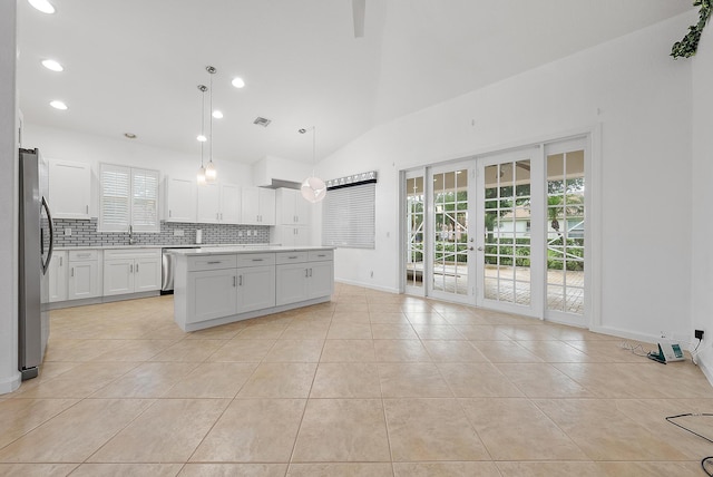 kitchen featuring pendant lighting, white cabinets, lofted ceiling, stainless steel fridge, and a center island