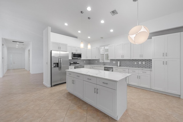 kitchen featuring light stone countertops, white cabinetry, appliances with stainless steel finishes, and hanging light fixtures