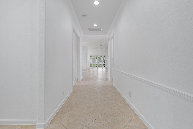 corridor with crown molding and light tile patterned floors