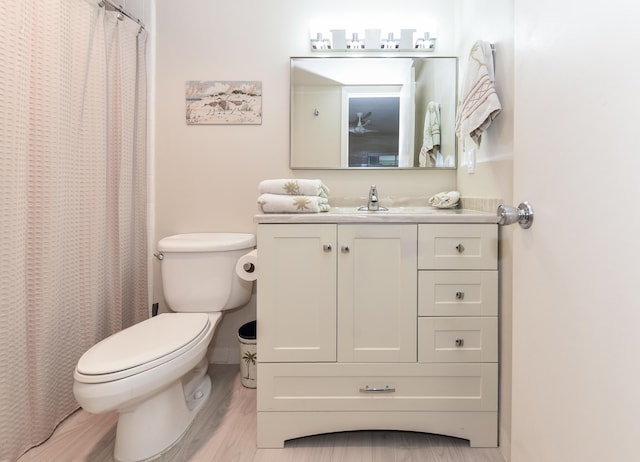 bathroom with toilet, vanity, hardwood / wood-style floors, and curtained shower