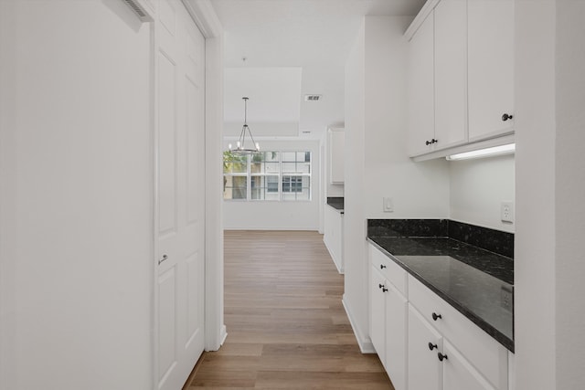 kitchen with dark stone countertops, light hardwood / wood-style floors, and white cabinetry