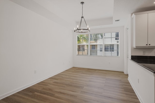 unfurnished dining area with light wood-type flooring and a chandelier