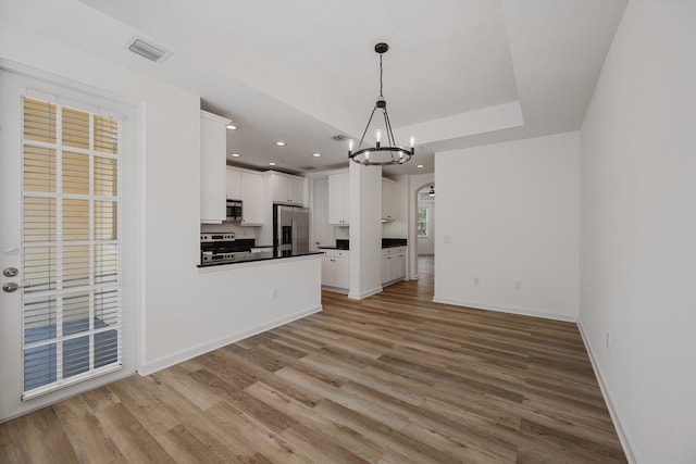 kitchen featuring appliances with stainless steel finishes, white cabinets, pendant lighting, an inviting chandelier, and light hardwood / wood-style flooring