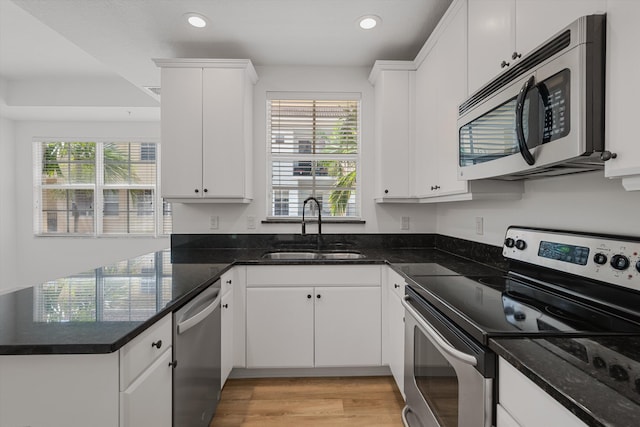 kitchen featuring stainless steel appliances, white cabinets, a wealth of natural light, and sink