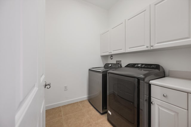 laundry room with light tile patterned floors, independent washer and dryer, and cabinets