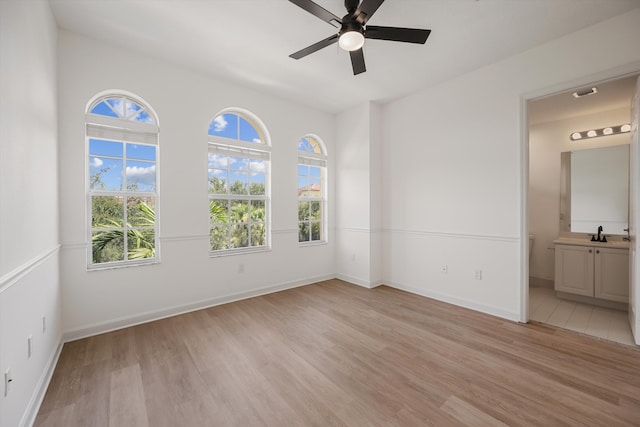 spare room featuring ceiling fan, light hardwood / wood-style flooring, sink, and a healthy amount of sunlight