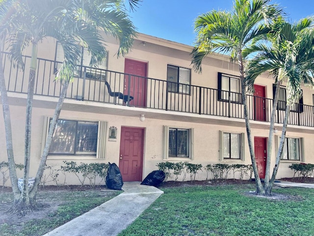 view of property with a balcony and a front yard