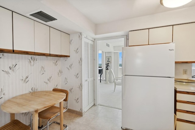 kitchen with white cabinetry, light tile patterned flooring, and white refrigerator