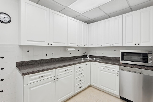 kitchen featuring sink, white cabinets, light tile patterned floors, appliances with stainless steel finishes, and a paneled ceiling