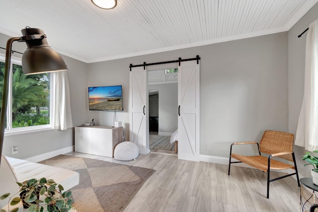 sitting room with ornamental molding, light wood-type flooring, and a barn door