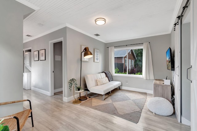 sitting room with ornamental molding, light hardwood / wood-style flooring, and a barn door