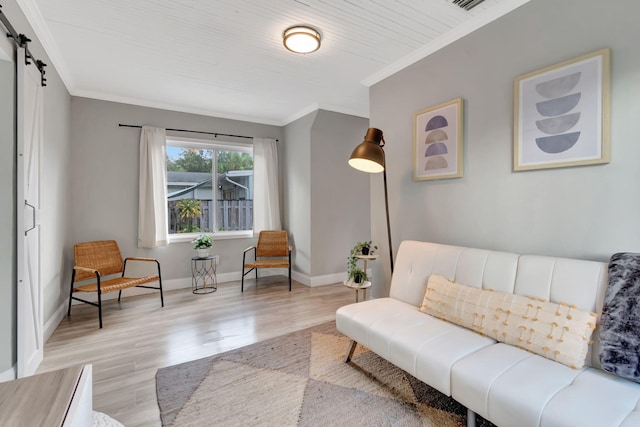 sitting room featuring ornamental molding, light hardwood / wood-style floors, and a barn door