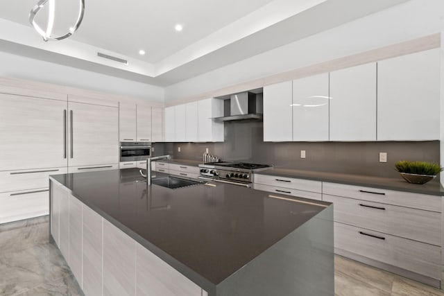 kitchen with a large island, wall chimney range hood, white cabinets, and appliances with stainless steel finishes