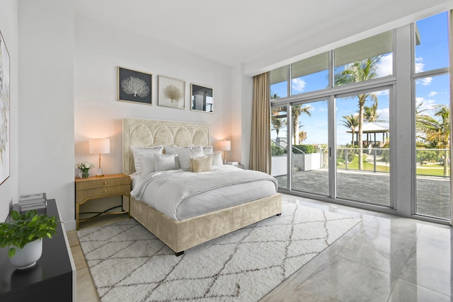 bedroom with expansive windows, a high ceiling, and access to outside