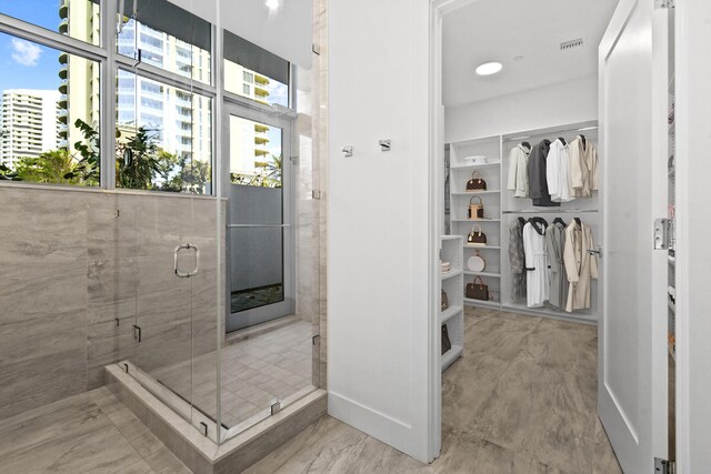 full bath featuring baseboards, visible vents, a shower stall, and a walk in closet
