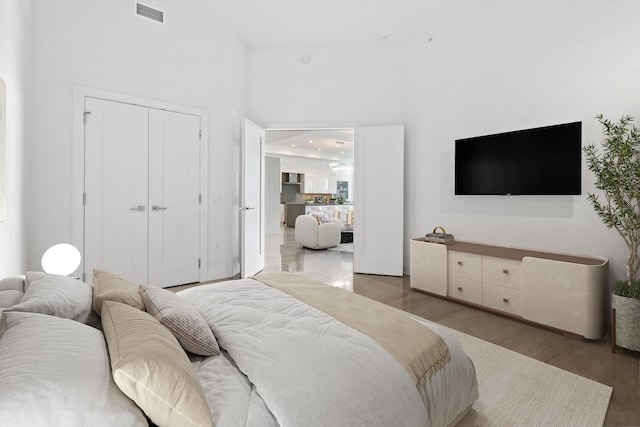 bedroom featuring wood finished floors, a closet, a high ceiling, visible vents, and recessed lighting