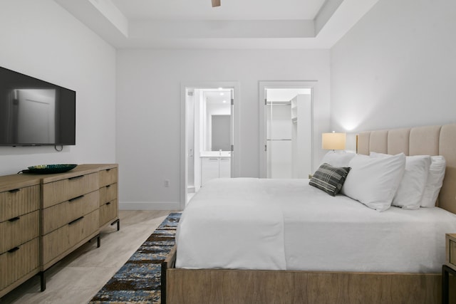 bedroom with a walk in closet, a tray ceiling, connected bathroom, and a closet