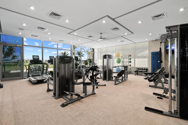 exercise room with expansive windows, light colored carpet, and ceiling fan