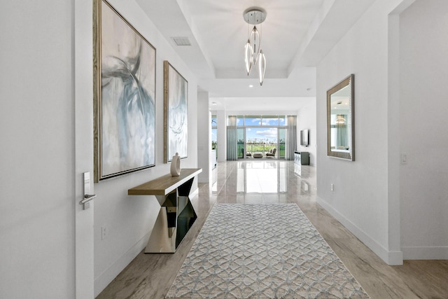hall featuring baseboards, visible vents, and an inviting chandelier
