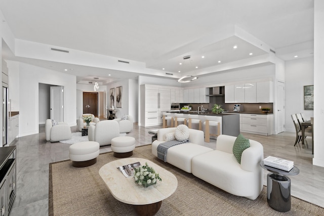 living area featuring a tray ceiling, visible vents, baseboards, and recessed lighting