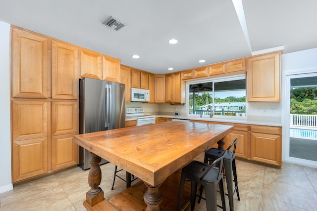 1121 SW Pine Tree Ln, Palm City, FL 34990 - kitchen featuring white appliances, light countertops, a sink, recessed lighting, and light brown cabinets