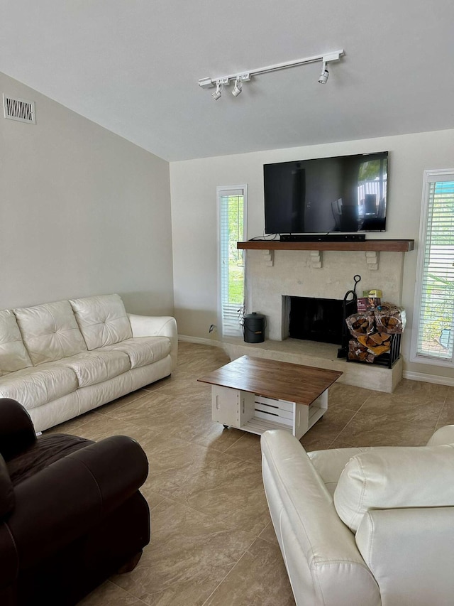 1121 SW Pine Tree Ln, Palm City, FL 34990 - tiled living room featuring rail lighting, baseboards, and a fireplace with raised hearth