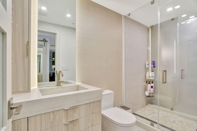 bathroom with vanity, a shower with door, and toilet