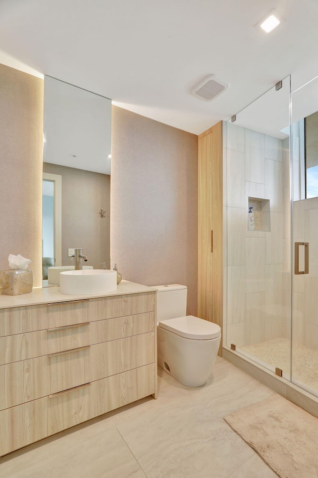 bathroom with vanity, toilet, and a shower with door