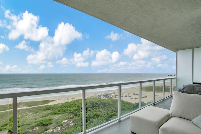 balcony with a water view and a view of the beach